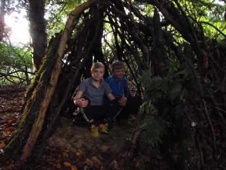 Two boys sitting in their den made of sticks