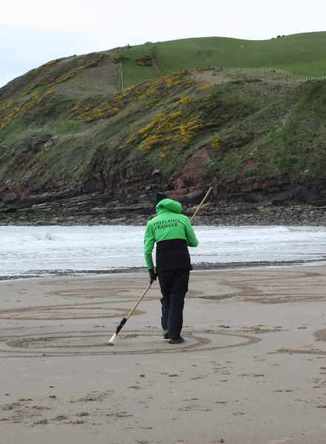 Freelance Ranger raking sand into patterns on beach