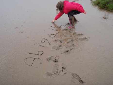 Girl writing her name in the mud
