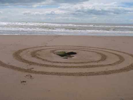 A spiral raked in sand leading to a rock in the middle