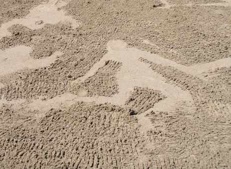 Sand raked to leave figures which look as though they are holding hands and dancing