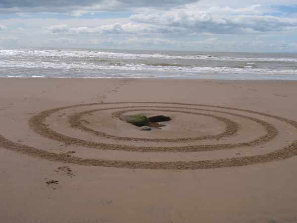 Spiral pattern raked on a beach with a stone at the centre